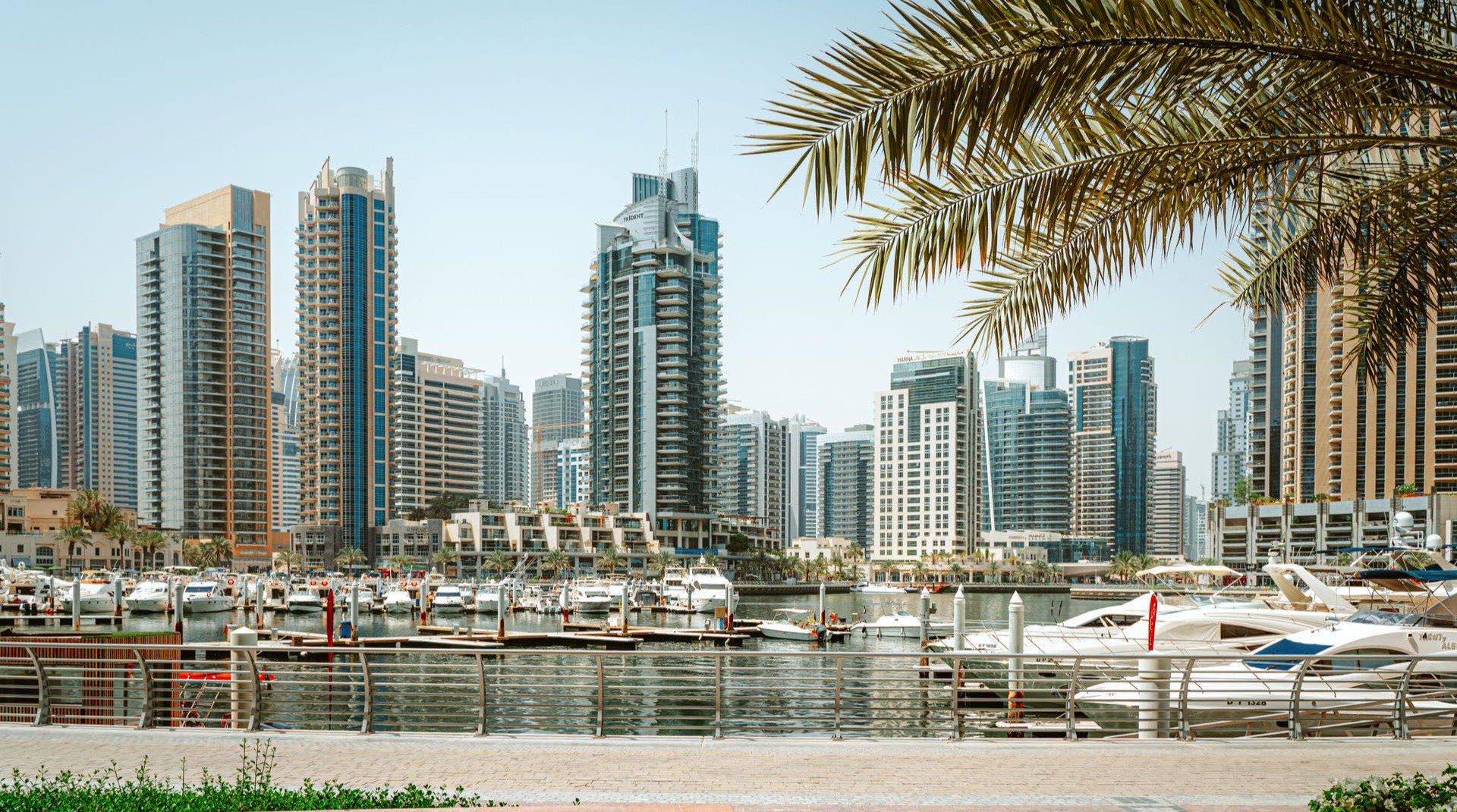Waterfront-Hochhäuser von Dubai Maritime City auf der Halbinsel zwischen Port Rashid und den Drydocks in der Abenddämmerung, mit Yachten und ruhigem Wasser im Vordergrund